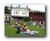 A group of people sitting on the grass in front of a building

Description automatically generated with medium confidence